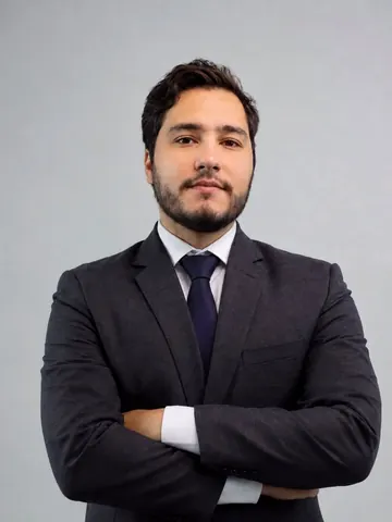 Advogado Lucas Castro, de terno, em fundo cinza